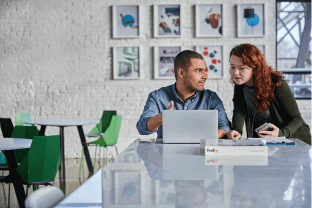 Three people working around a laptop