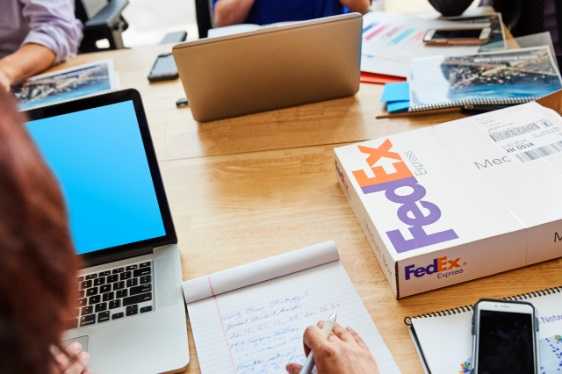 An office table with laptops and FedEx boxes