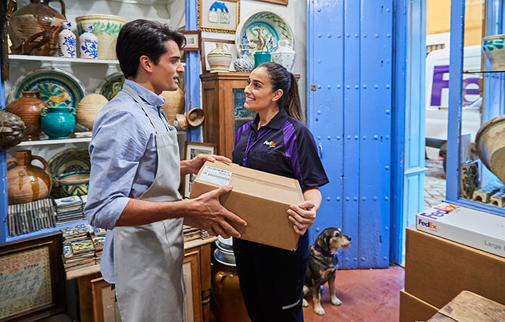 FedEx driver handing a package to a shopkeeper