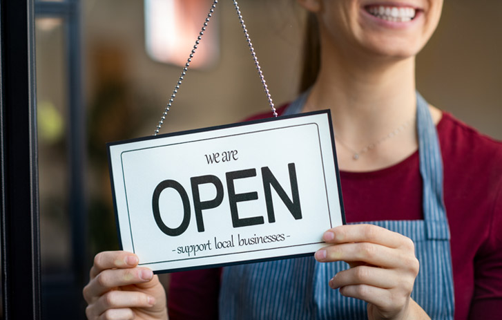 woman flipping "open" sign of business
