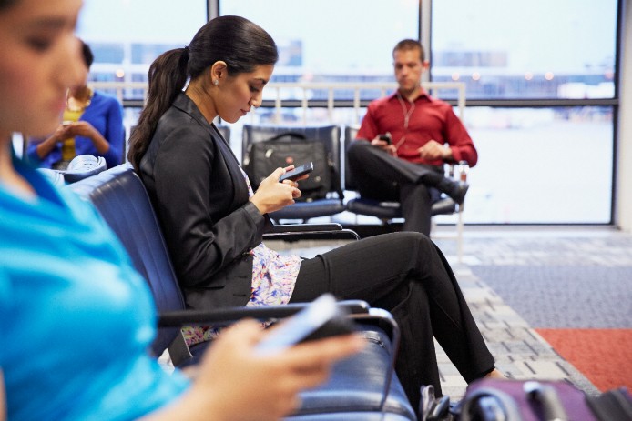 People sitting and looking at their phones in an airport