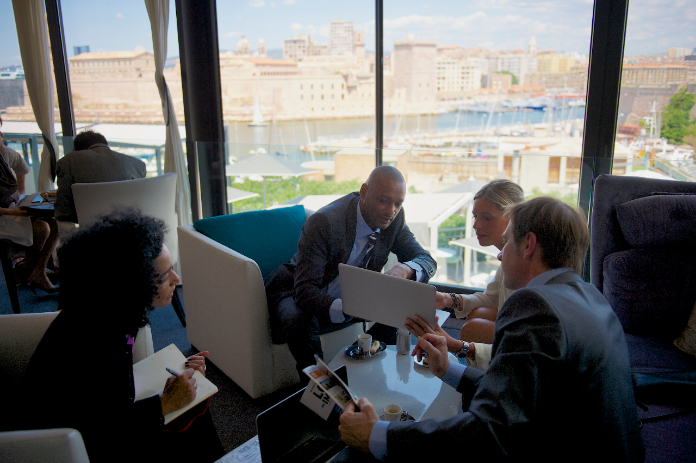 4 professionals discussing info on tablet