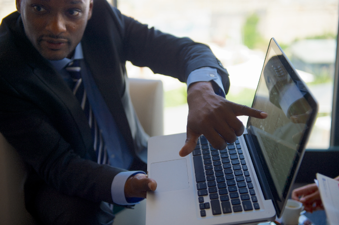 businessman pointing at info on laptop
