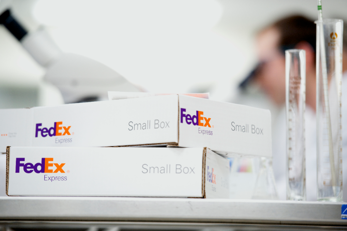 FedEx Small Boxes on counter with beakers and a microscope