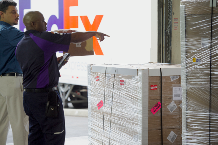 FedEx team member and customer sorting through packages in warehouse