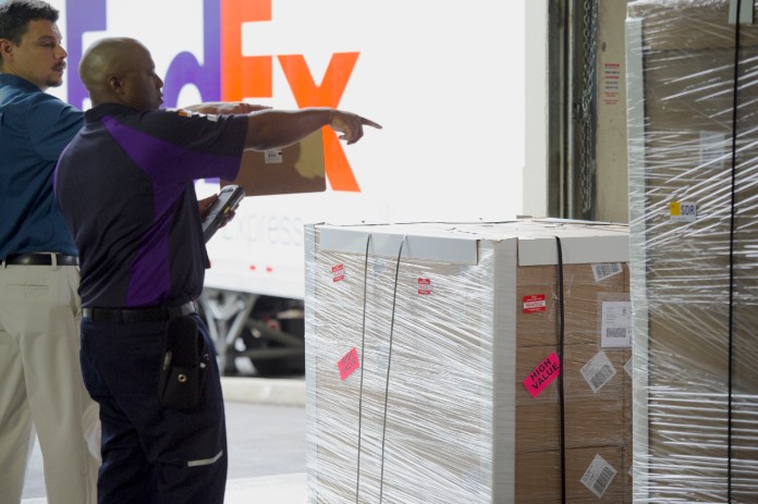 FedEx team member and customer sorting through packages in warehouse