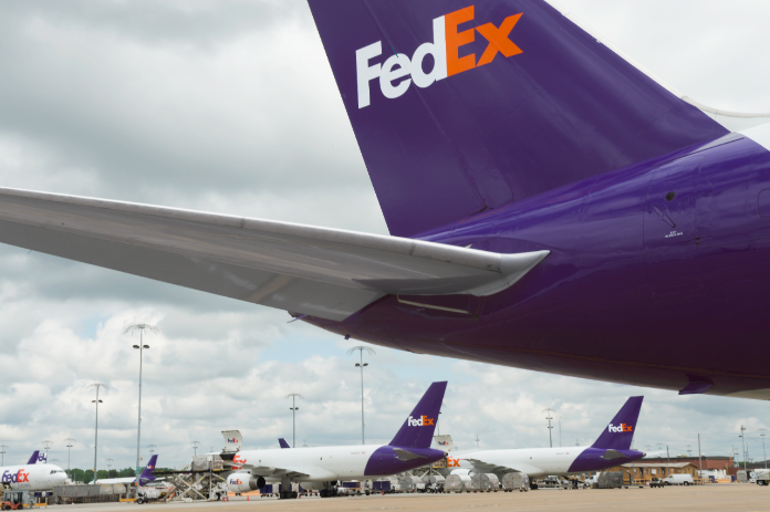 FedEx airplanes sit on an airport tarmac.