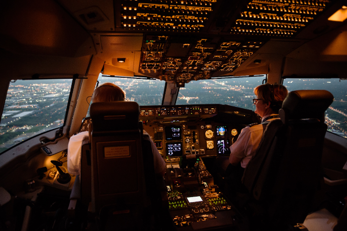 Two pilots look out the window while flying above a city