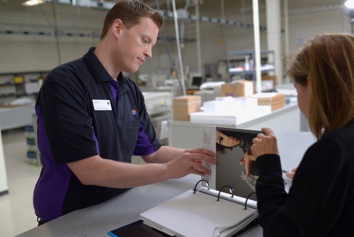 Fedex employee shows customer printing capabilities in a three-ring binder.