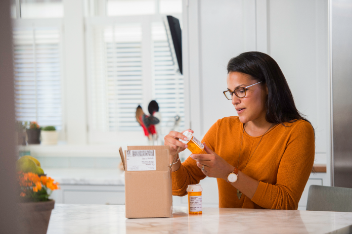 A customer looks closely at a bottle of medication that she has removed from its package.
