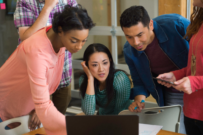employees in an office setting viewing a demo on a laptop