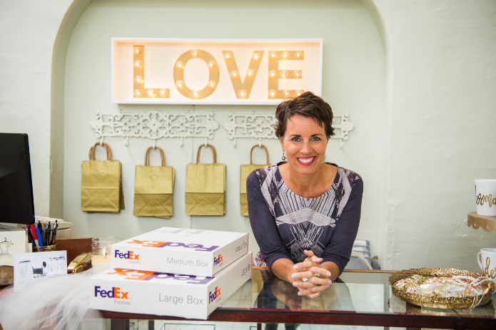 Boutique employee smiling next to FedEx boxes