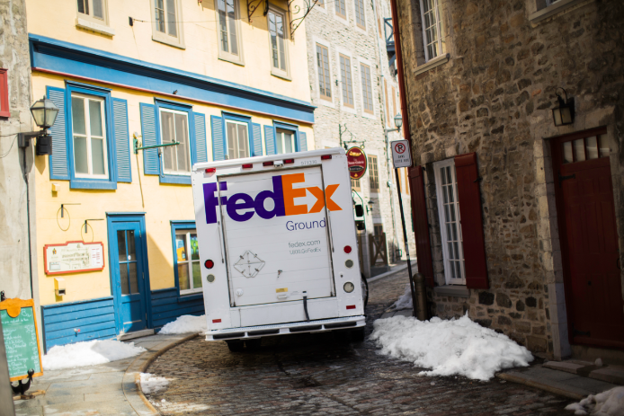 A FedEx Ground delivery truck driving along a narrow Canadian alleyway