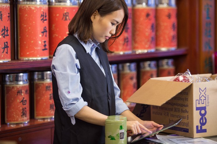 woman in store looking at laptop next to FedEx box