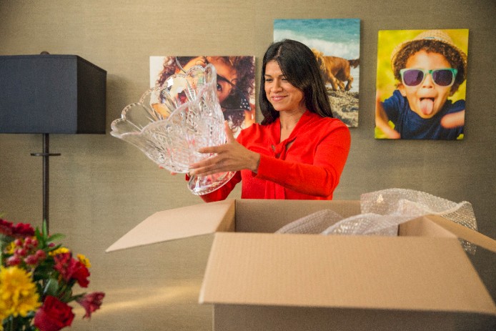 Woman smiling and unpacking glass punch bowl from large brown box