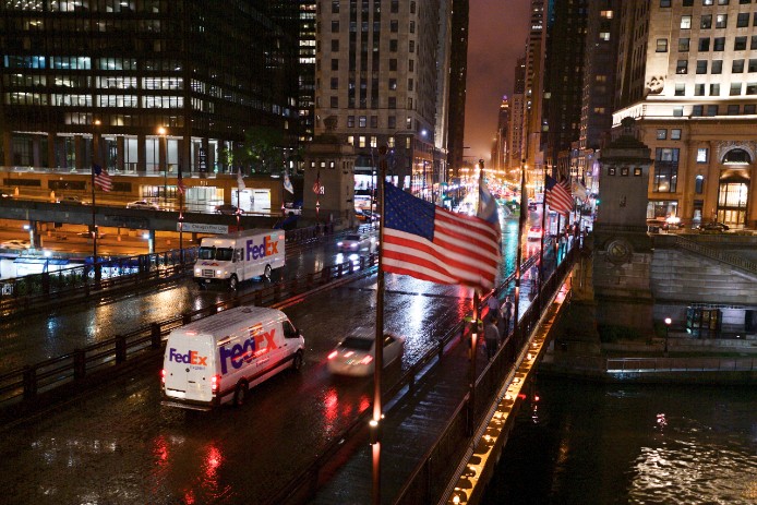 FedEx trucks in city with flags