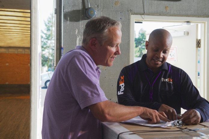 fedex driver and warehouse employee reviewing manifest