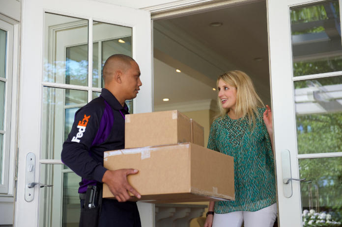 A woman receives package delivery at the front door.