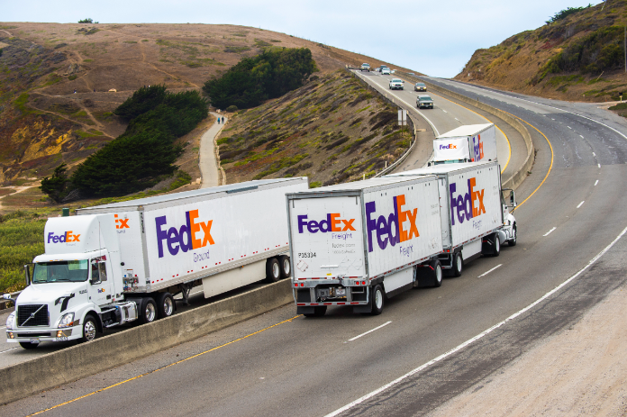 FedEx freight trucks drive north and south along a highway.