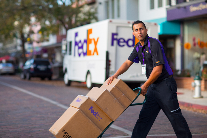 A FedEx courier crosses a city street.