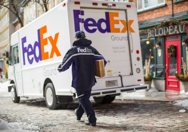 A FedEx courier walks toward his FedEx Ground delivery truck.