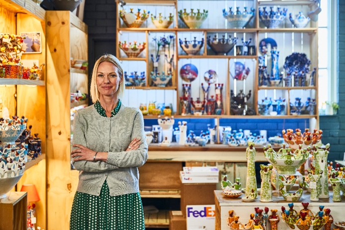 The owner of a ceramics and pottery shop smiles with pride.