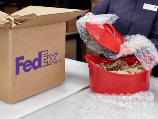 FedEx Office employee using bubble wrap and paper to securely pack a Dutch oven