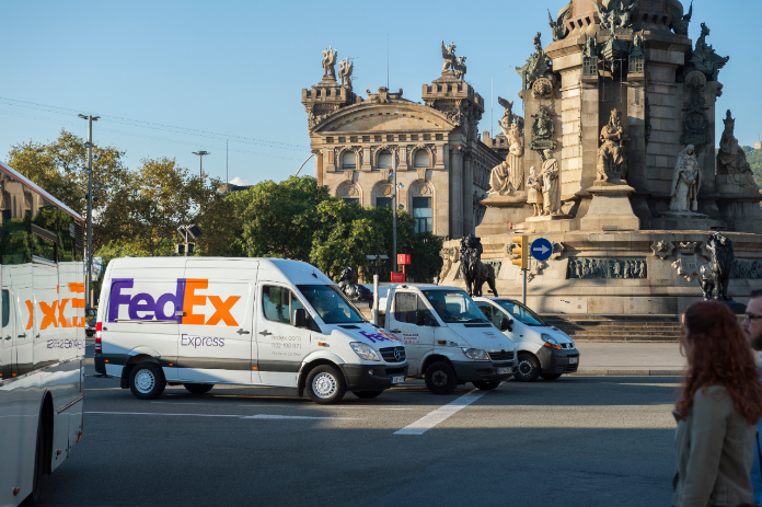 FedEx delivery vans park in front of a European cathedral.