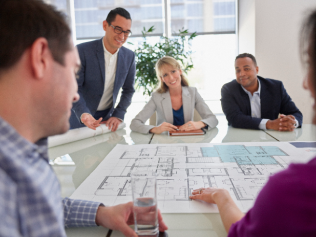 Meeting over an architectural print Employees having a meeting over an architectural print
