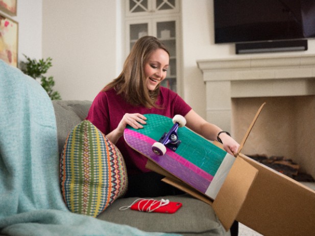 Woman unpacking skateboard from brown box