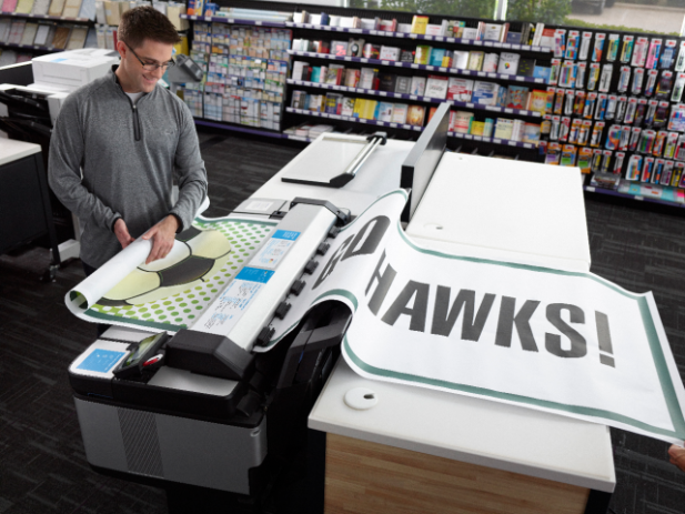 Oversized Prints Fan pulling oversize print of team name from printer