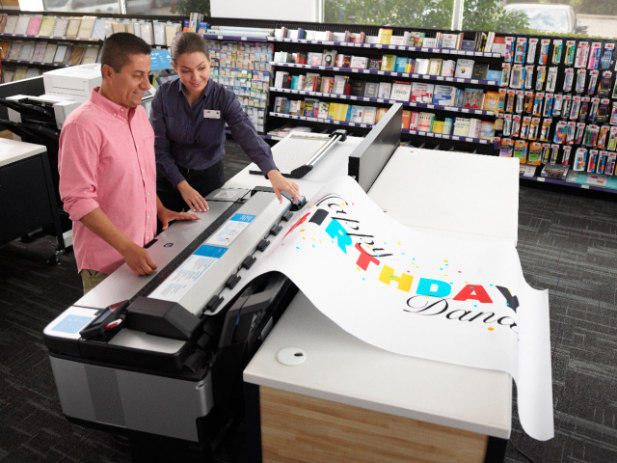Oversized print of happy birthday Friend pulling an oversize print of happy birthday from printer