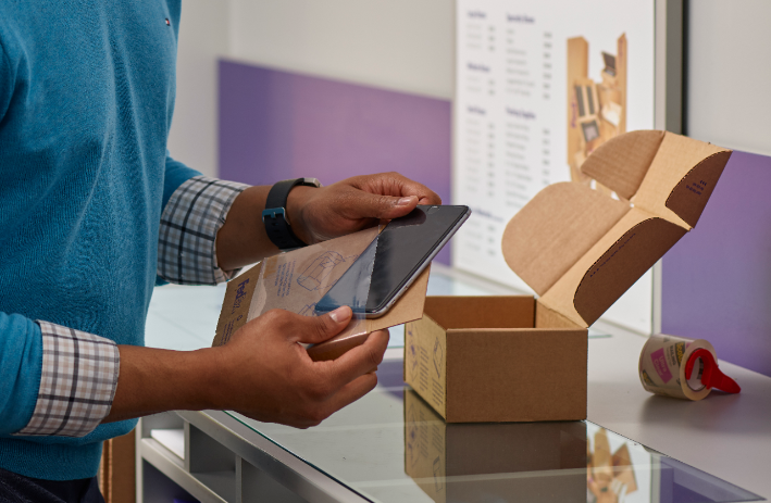 A customer packs his cell phone into a protective shipping box