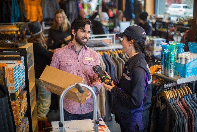 Clothing store employee receiving package from FedEx courier