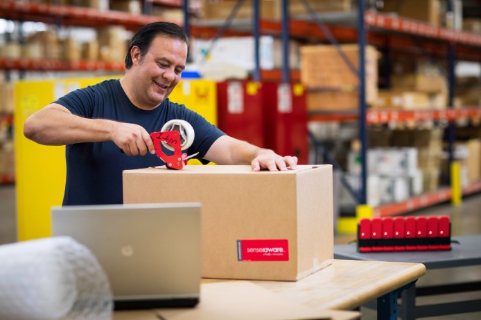 Man tapes box labeled SenseAware in warehouse