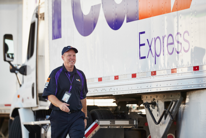 Courier walks beside FedEx Express truck