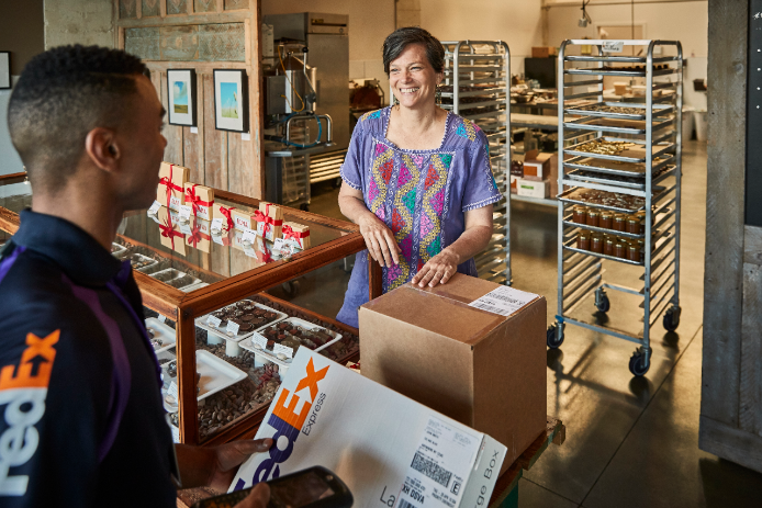 A FedEx courier picking up a box from a customer