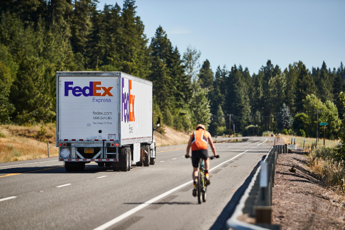 FedEx Express truck driving by cyclist