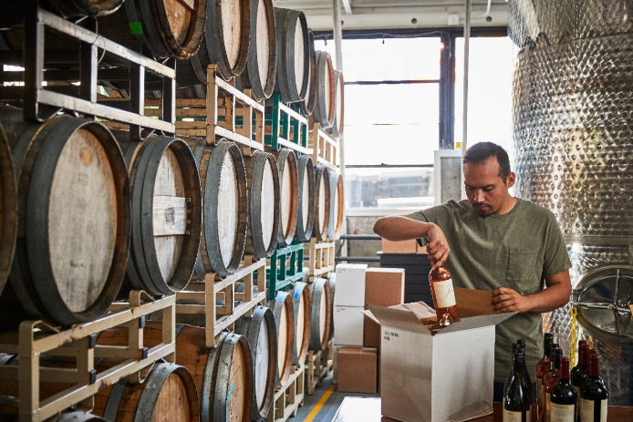 A small business owner opens a case of wine in his wine cellar.