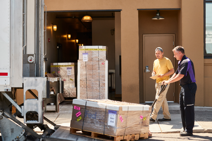 A FedEx courier delivers a pallette to a small business owner.