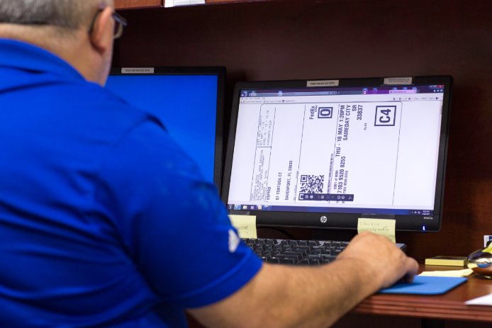 Man in blue shirt creates shipping label on computer