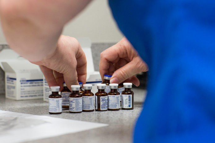 Person in lab picks up small bottles with both hands