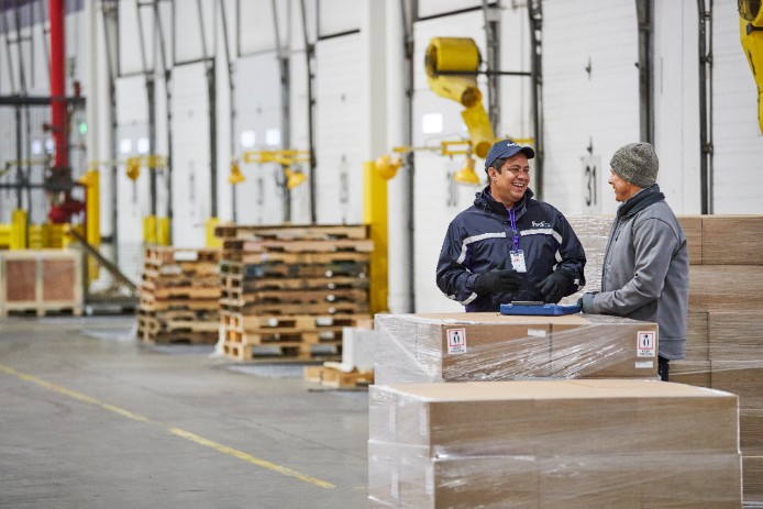 Courier smiles next to large cardboard boxes