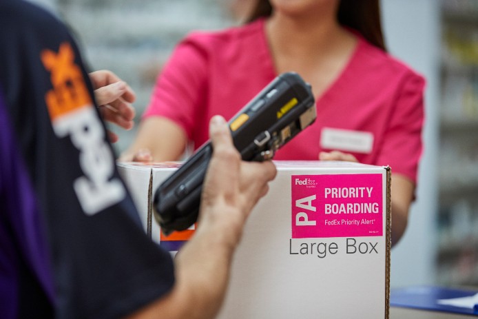 A FedEx courier scans a priority boarding package