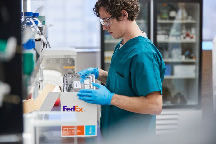 A pharmacists packs expired medications into a FedEx box