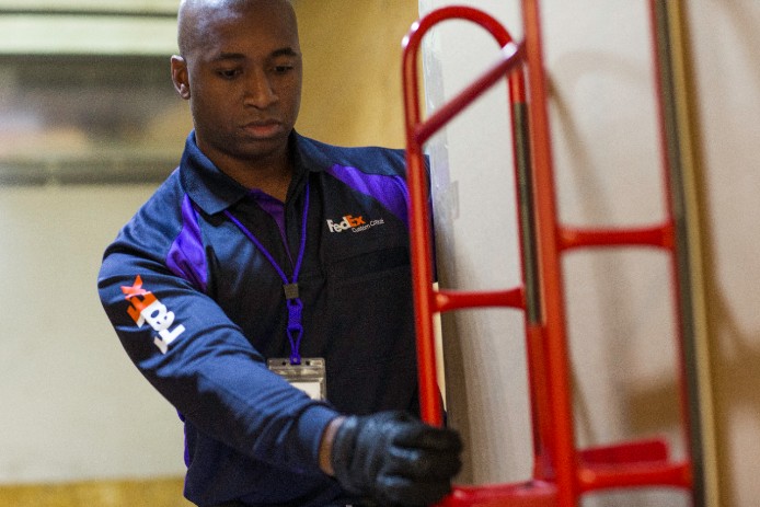 FedEx Courier placing hand cart against wall
