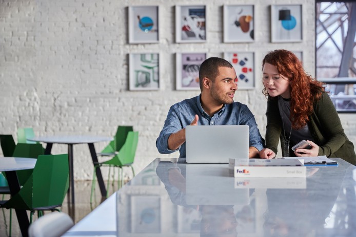 Two people discussing content on laptop.