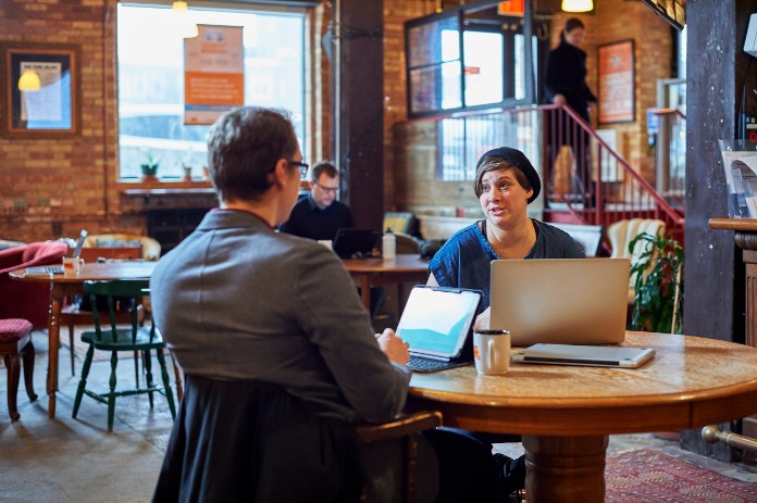Two people sitting at indoor cafe with laptops