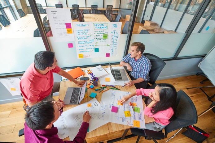 Multiple people working around a desk.