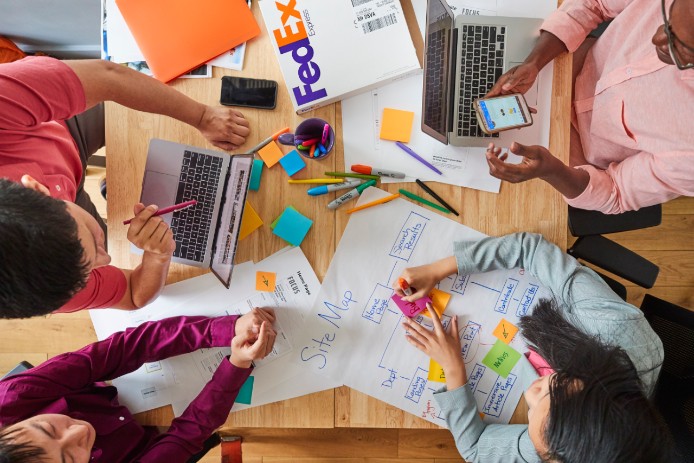 Looking down on 4 people in a meeting writing on sticky notes